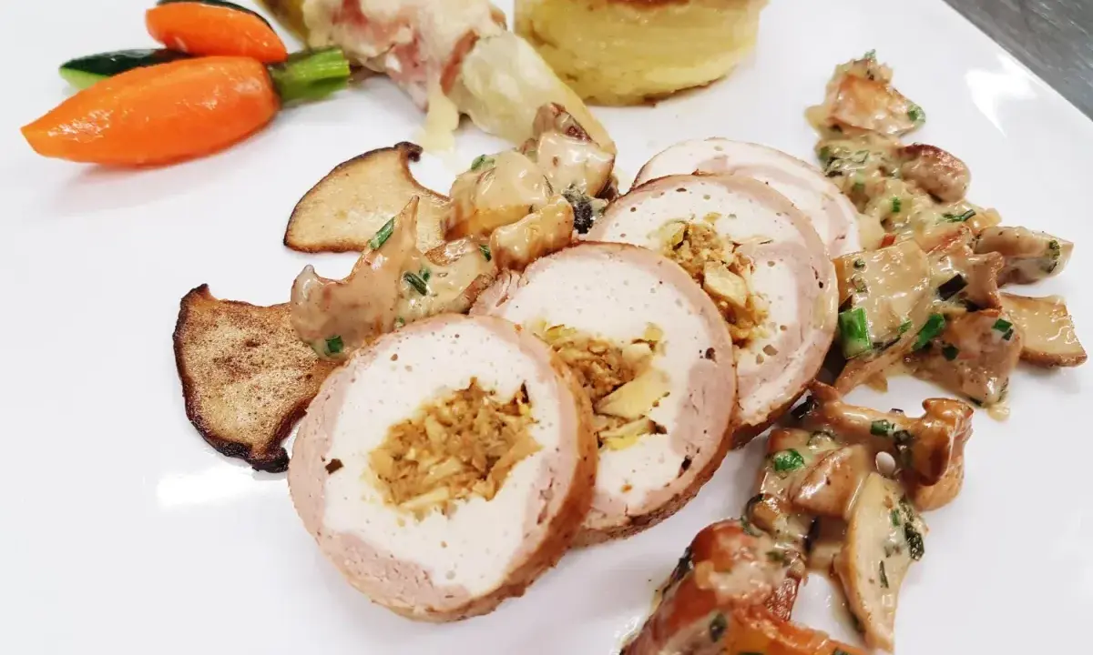 Délicieuse ballotine de volaille farcie, servie avec des champignons, des légumes croquants et une purée de pommes de terre gratinée.