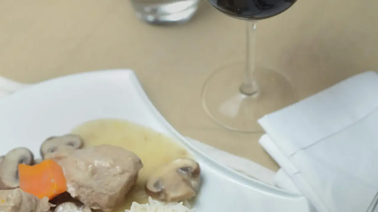 Un verre de vin rouge accompagne une blanquette de veau avec riz et champignons. Quel vin avec une blanquette de veau ?