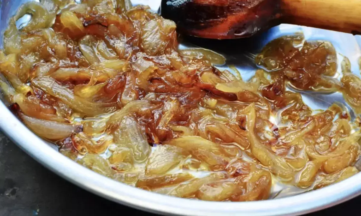 Oignons nouveaux caramélisés dans une poêle, prêts pour une délicieuse recette. La cuisson lente révèle leur douceur.