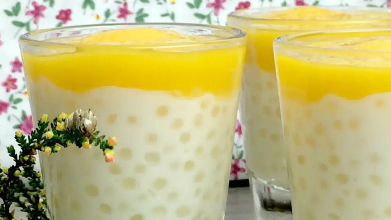 Trois verres de tapioca au lait de coco, surmontés d'une purée jaune, avec une petite branche de bruyère en premier plan.