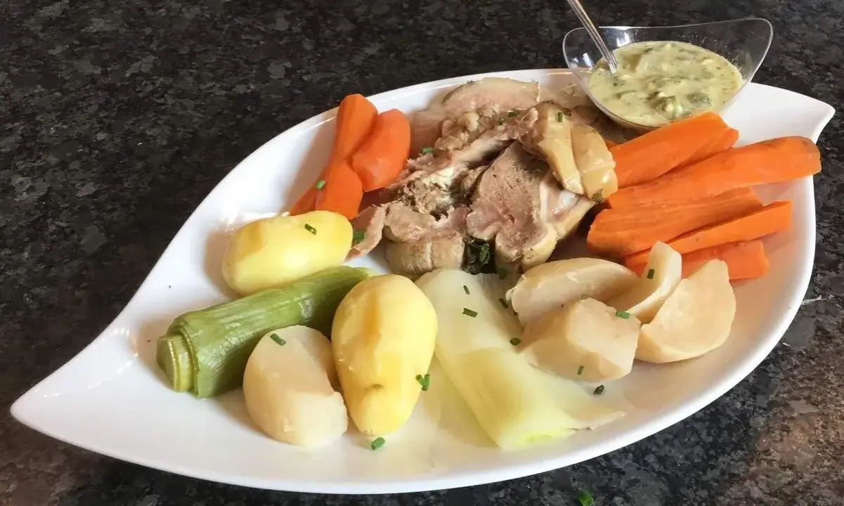 Tête de veau savoureuse accompagnée de carottes, pommes de terre et poireaux, le tout servi avec une sauce tartare crémeuse.