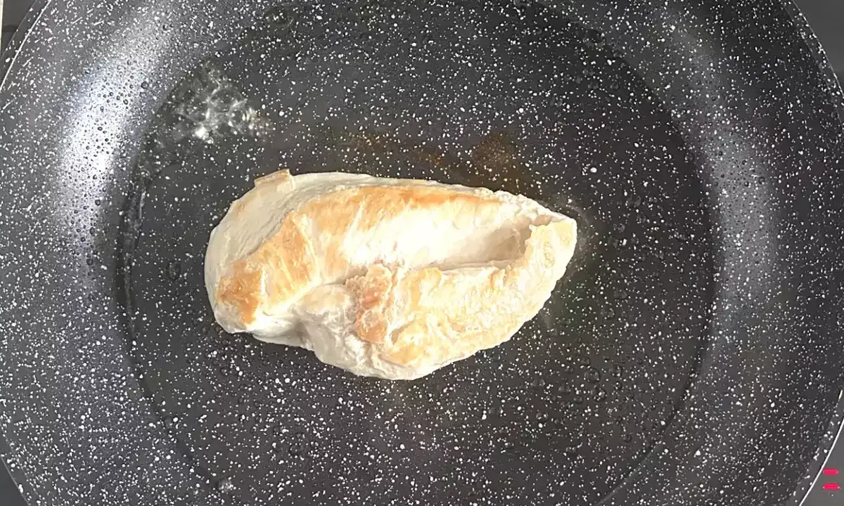 Escalope de poulet dorée dans une poêle, étape clé d'une recette facile et savoureuse.