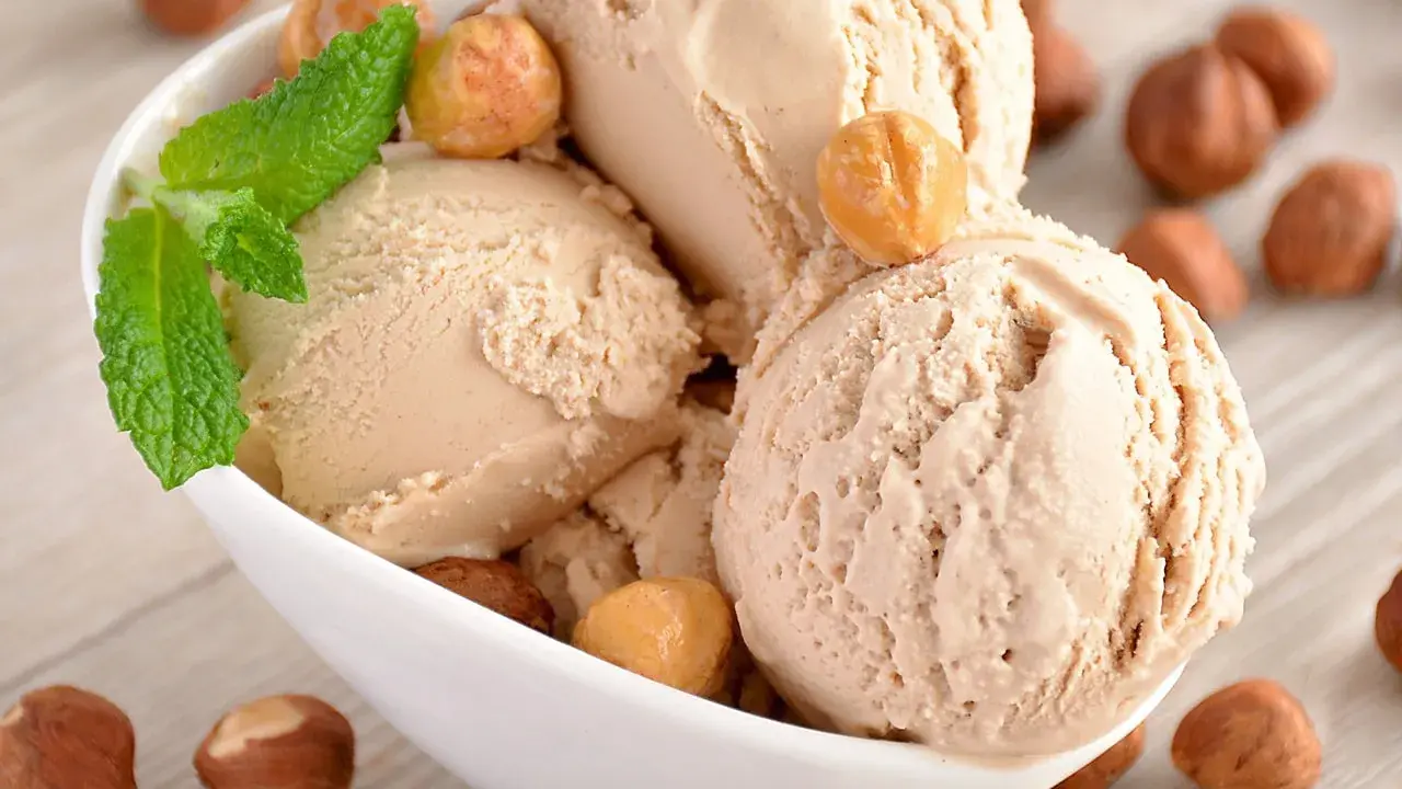 Gourmande recette glace noisette italienne. Boule crémeuse, garnie de noisettes grillées et d'une touche de menthe fraîche.