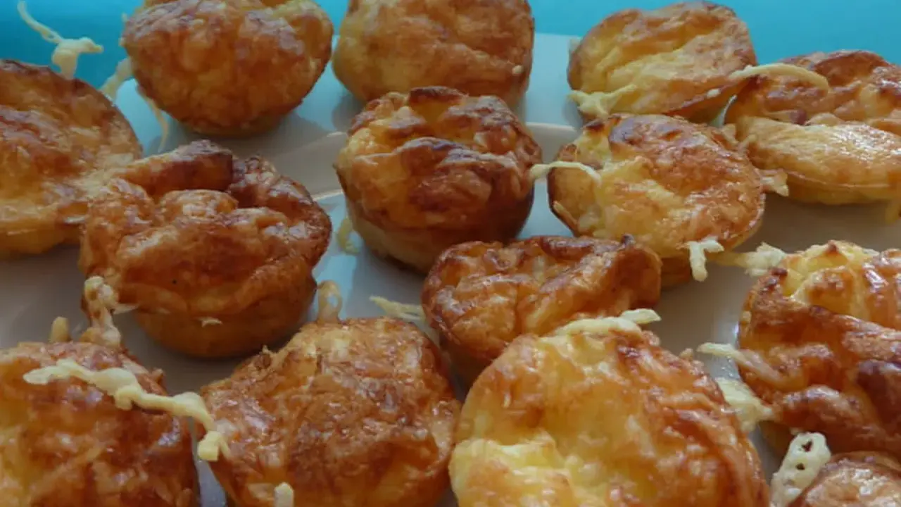Une assiette de mini quiches sans pâte dorées et appétissantes, garnies de fromage fondu. Parfaites pour un apéritif gourmand.