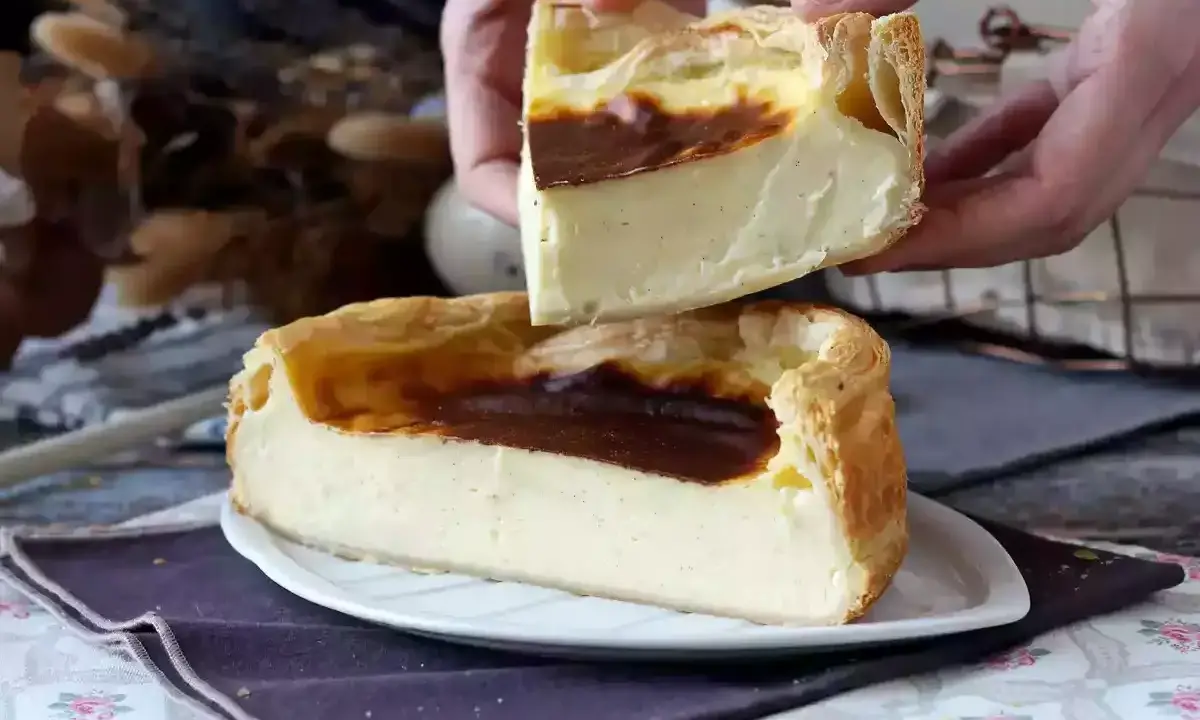 Un flan pâtissier aux bords dorés et à la crème onctueuse, une part est soulevée, révélant sa texture.