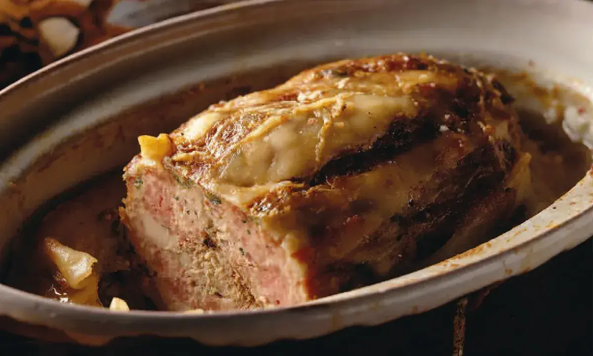 Tranche de terrine de canard dorée et appétissante, servie dans un plat en céramique.
