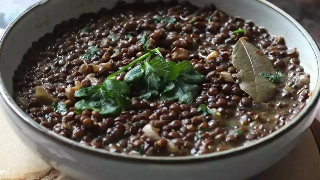 Un plat de cuisson lentilles vertes, garni de persil frais et d'une feuille de laurier.