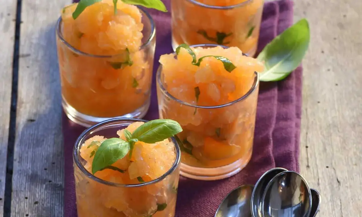 Recette soupe de melon apéritif : sorbet de melon frais aux feuilles de basilic dans des verres, prêt à déguster.