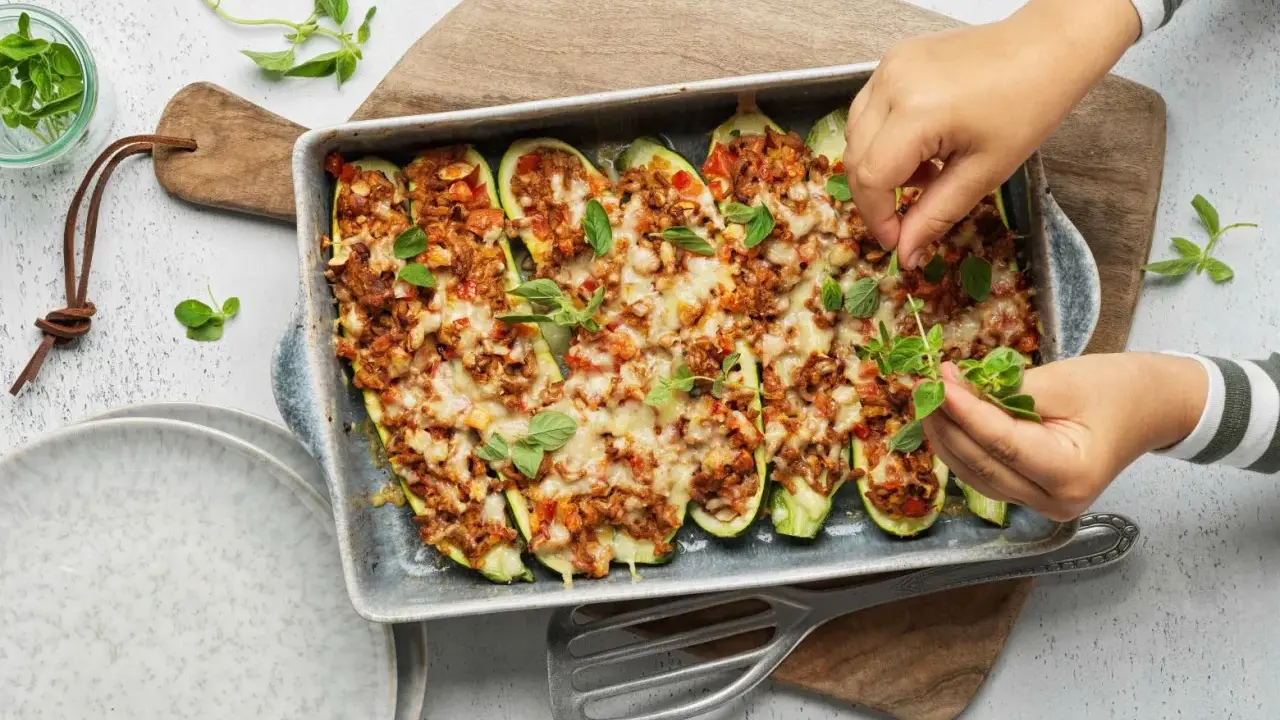 Courgettes farcies à la viande hachée, gratinées au fromage et garnies de feuilles de basilic frais. Un plat savoureux prêt à être dégusté.
