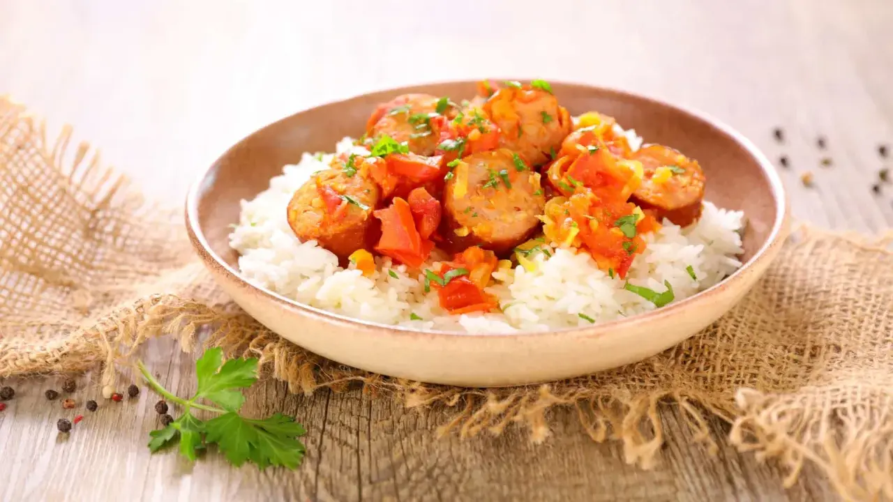Un plat de rougail saucisse sur du riz blanc, garni de persil. Quel vin avec rougail saucisse ? Un vin fruité et léger serait parfait.
