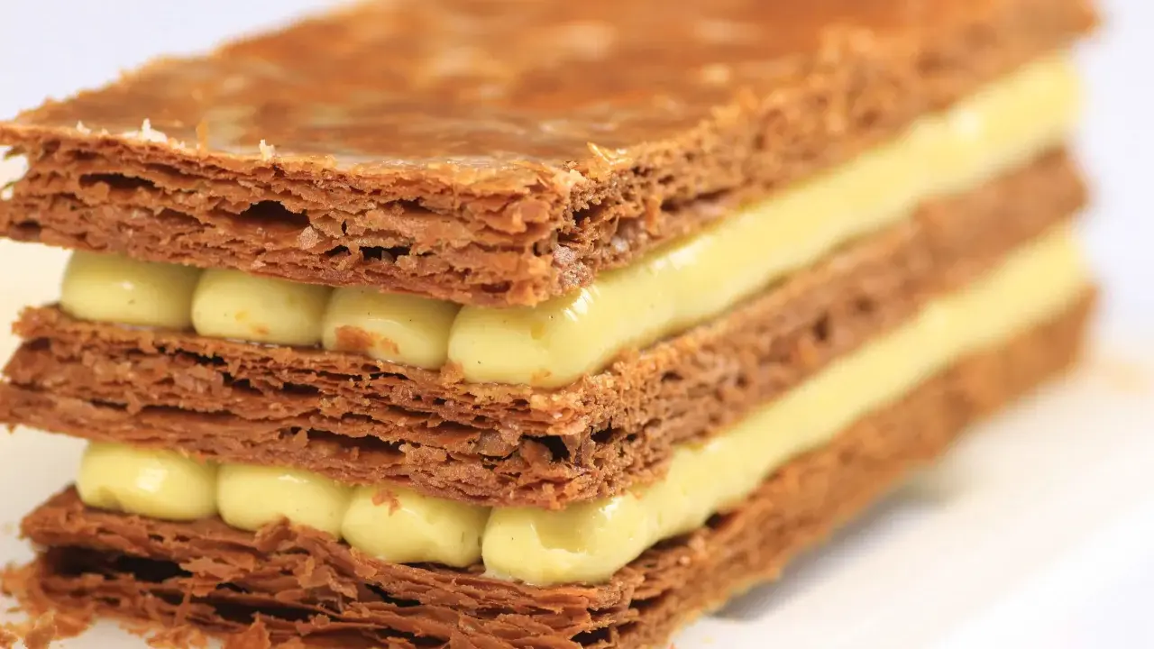 Un millefeuille croustillant aux couches de pâte feuilletée dorée et de crème pâtissière onctueuse. Une recette de mille feuille qui fait rêver.