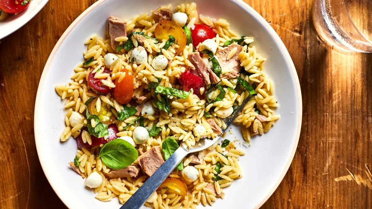 Salade de pâtes orzo avec thon, tomates cerises, billes de mozzarella et basilic frais, parfaite pour un pique-nique ensoleillé.