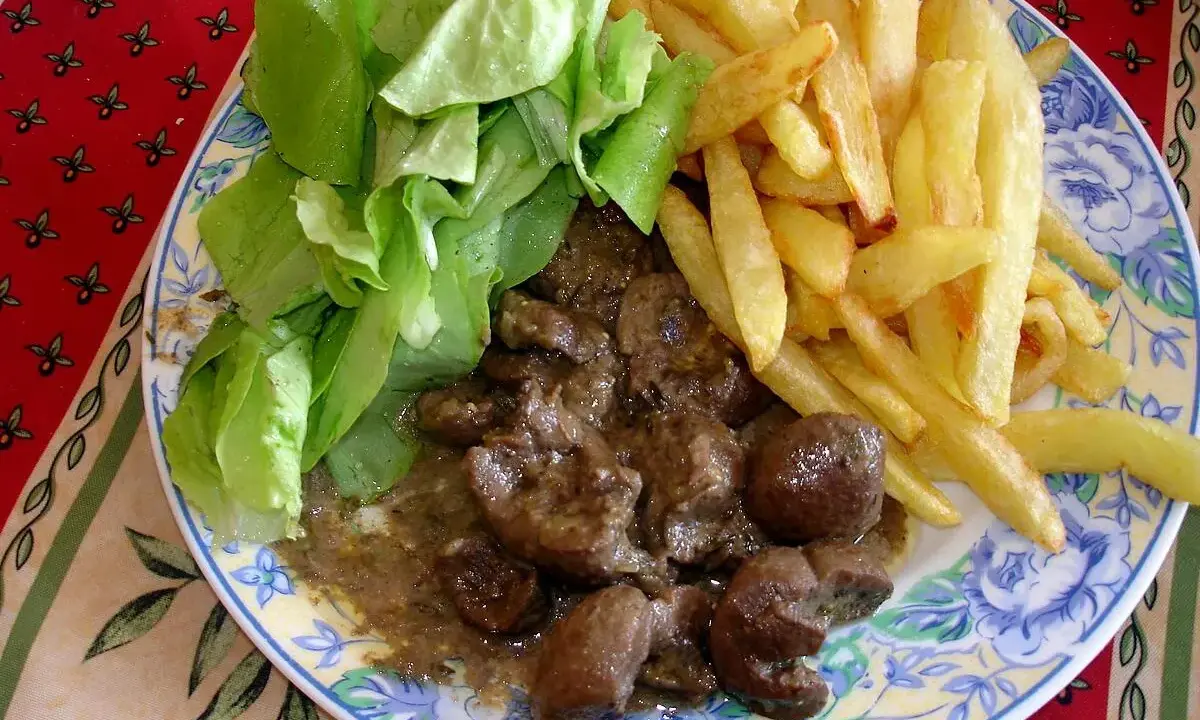 Assiette de rognon de boeuf en sauce, frites dorées et salade verte fraîche. Un plat savoureux pour les amateurs de gibier.