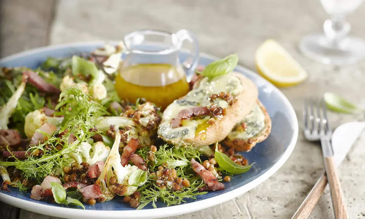 Salade verte avec chou-fleur rôti, lentilles, lardons et toasts au fromage bleu. Une idée de quoi mettre dans une salade verte pour un repas savoureux.