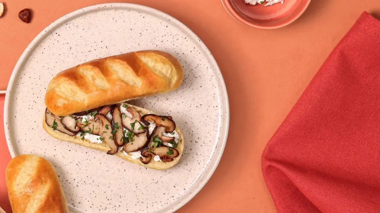 Délicieux sandwich pain au lait garni de champignons sautés et de fromage frais, parsemé de persil.