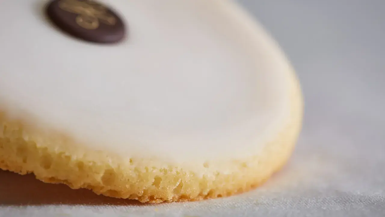 Un palet de dame, biscuit sablé glacé de blanc, orné d'un médaillon chocolat doré.