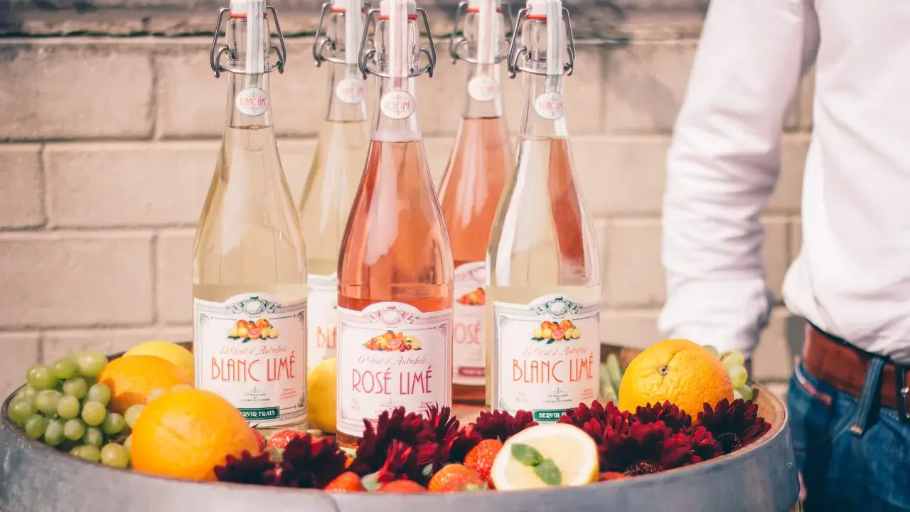 Bouteilles de cocktail vin blanc limonade citron, fruits frais et fleurs dans un tonneau.