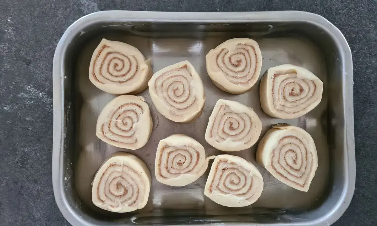 Dix roulés à la cannelle prêts pour la cuisson, une étape clé de la recette de cinnamon rolls.