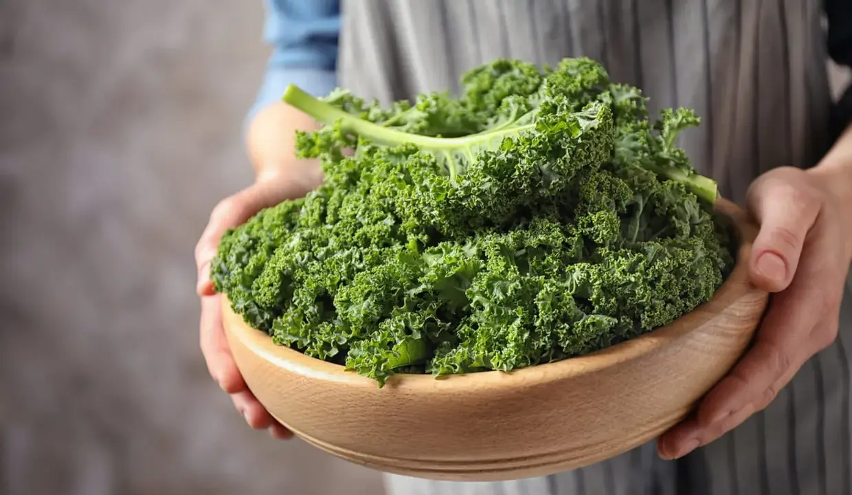 Un bol en bois rempli de chou kale frais, prêt pour une délicieuse recette italienne.