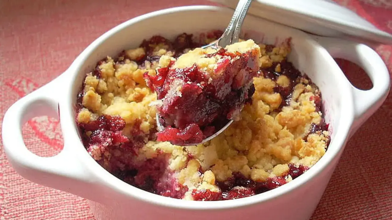 Cuillère de crumble fruits rouges, un délice croustillant et fruité dans un ramequin blanc.