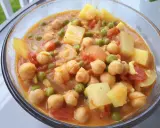 Un savoureux curry de petit pois avec des pois chiches et des morceaux de pommes de terre dans une sauce orangée.