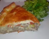 Une part de tourte à la viande grand-mère, dorée et généreuse, servie avec une salade verte croquante. Un délice réconfortant.