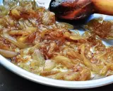 Oignons nouveaux caramélisés dans une poêle, prêts pour une délicieuse recette. La cuisson lente révèle leur douceur.
