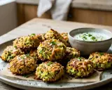 Petits beignets de courgettes dorés, parfaits pour un apéritif facile. Servi avec une sauce crémeuse.