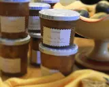 Plusieurs pots de confiture maison, dont une délicieuse confiture de pêches de vignes, sont alignés sur une table en bois.