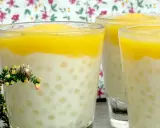 Trois verres de tapioca au lait de coco, surmontés d'une purée jaune, avec une petite branche de bruyère en premier plan.