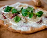 Délicieuse tarte flambée végétarienne garnie de fromage de chèvre, oignons et herbes fraîches.