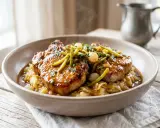 Délicieuse côte de porc charcutière, nappée d'une sauce onctueuse, servie sur un lit de purée et garnie de cornichons et d'oignons grelots.