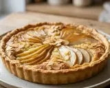 Une délicieuse amandine aux poires, garnie d'amandes effilées, sur une assiette en céramique.