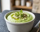 Un bol de purée de brocolis onctueuse, garnie de graines de tournesol, d'huile d'olive et de persil frais.