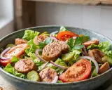 Salade de cervelas fraîche avec tomates, oignons rouges, cornichons et persil, assaisonnée d'une vinaigrette légère.