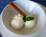 Deux boules de glace au citron onctueuse, garnies de menthe fraîche et d'un biscuit fin, dans un bol blanc.