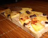 Tranche de tarte flambée sucrée aux pommes, cannelle et pépites de chocolat, posée sur un tapis de bambou.
