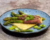 Asperge à la poêle enroulée de viande séchée, servie sur du pain grillé, garnie de persil frais et de morceaux d'asperges.