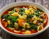 Soupe au pistou recette de chef : un plat coloré de légumes frais, pâtes et pesto, servi dans un bol blanc sur fond de bois.