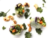 Trois rouleaux de printemps végétariens colorés, remplis de légumes frais et de noix de cajou grillées, parsemés de persil frais.