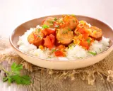 Un plat de rougail saucisse sur du riz blanc, garni de persil. Quel vin avec rougail saucisse ? Un vin fruité et léger serait parfait.