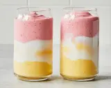 Deux verres de smoothie sans lait aux couches distinctes : jaune, blanc et rose.