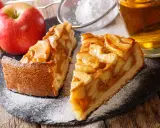 Deux parts de tarte aux pommes, saupoudrées de sucre glace, avec des pommes fraîches et un verre de cidre. Une belle idée de que faire avec des pommes.
