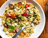 Salade de pâtes orzo avec thon, tomates cerises, billes de mozzarella et basilic frais, parfaite pour un pique-nique ensoleillé.