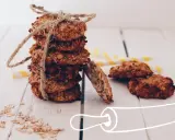 Pile de cookies healthy flocons d'avoine, liés par une cordelette. Quelques flocons éparpillés et des pailles rayées en arrière-plan.