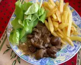 Assiette de rognon de boeuf en sauce, frites dorées et salade verte fraîche. Un plat savoureux pour les amateurs de gibier.