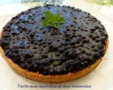 Tarte myrtille amande, une gourmandise aux myrtilles juteuses et à la pâte sablée aux amandes, décorée d'une touche de menthe fraîche.