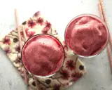 Deux verres remplis d'un onctueux milkshake fruit rouge, accompagnés de pailles roses et d'une serviette fleurie.