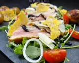 Délicieuse tagliata de veau, servie sur un lit de roquette avec des tomates cerises, des oignons et des tuiles de parmesan croustillantes.
