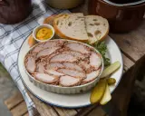 Tranches généreuses de rillettes de porc, servies avec du pain frais, de la moutarde et des cornichons. Un délice rustique.